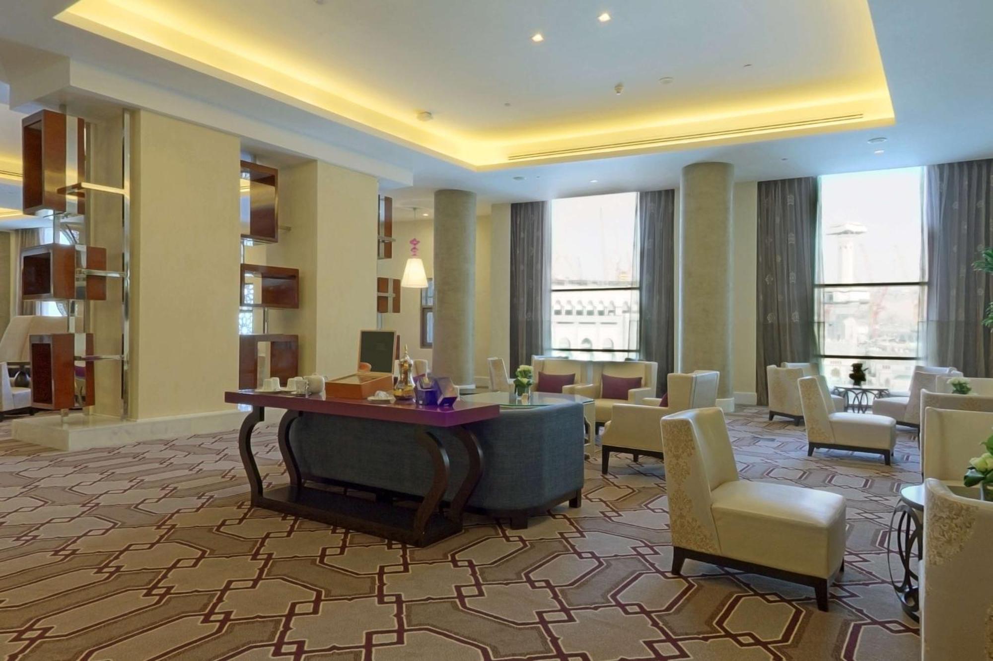 Hilton Suites Jabal Omar Makkah Mekka Exterior foto The photo shows a spacious and elegantly designed lounge area. The room features a modern aesthetic with soft lighting emanating from the ceiling. There are several comfortable chairs arranged around a central table, creating a welcoming seating area