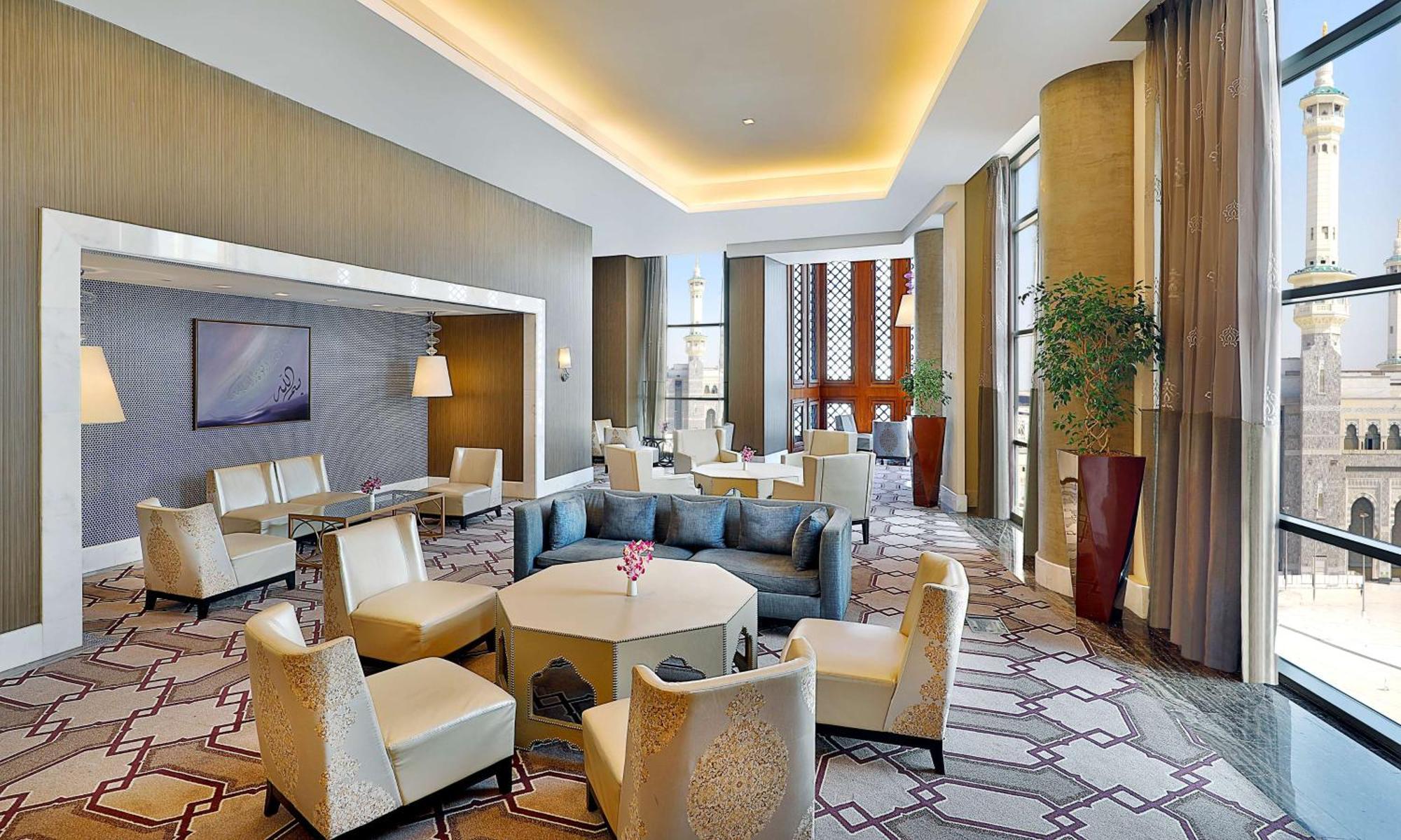 Hilton Suites Jabal Omar Makkah Mekka Exterior foto The photo depicts a stylish and modern lounge area. It features several seating arrangements, including a combination of light-colored armchairs and sofas, arranged around hexagonal and round tables. The decor is contemporary, with soft, warm lightin