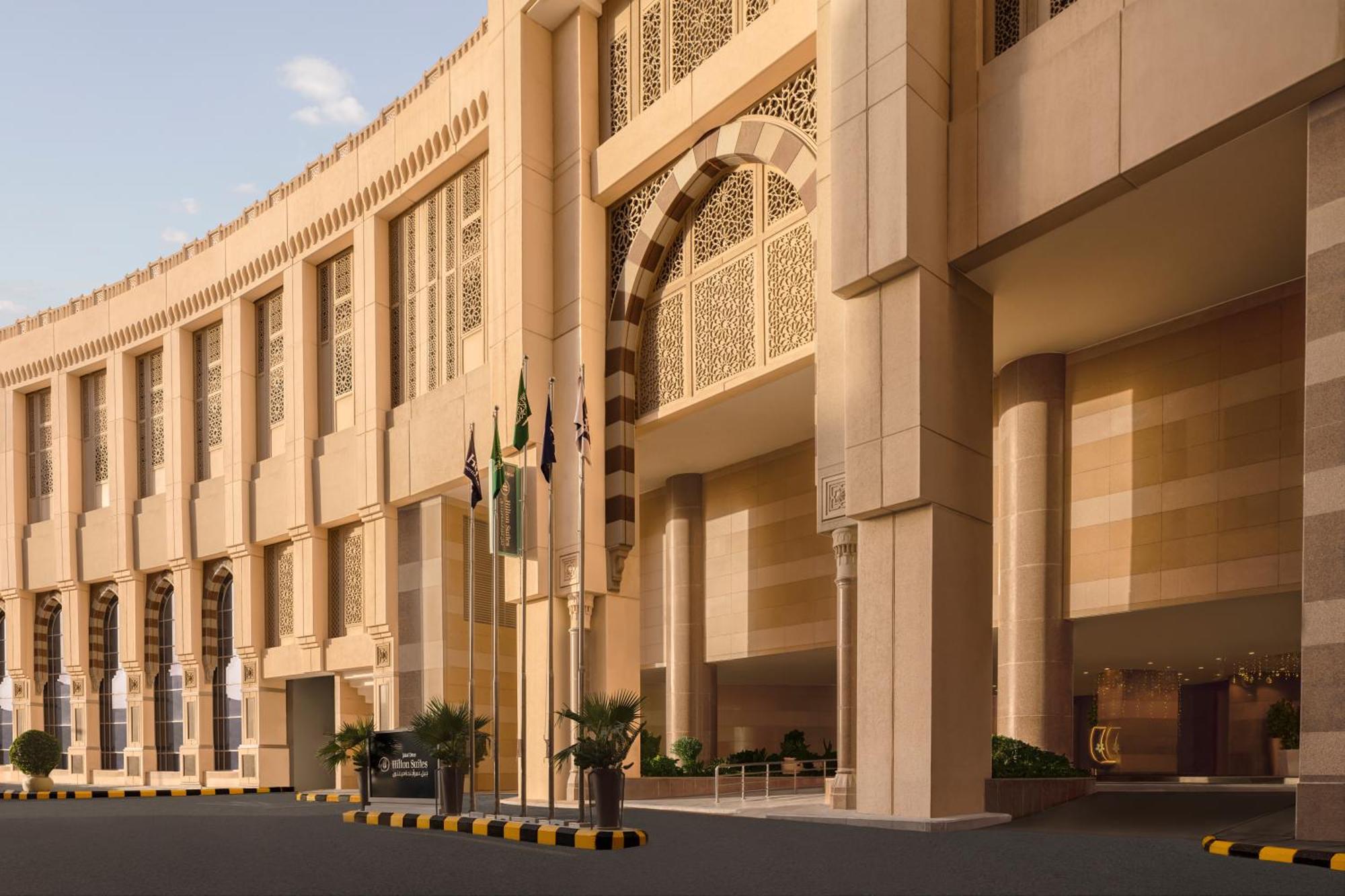 Hilton Suites Jabal Omar Makkah Mekka Exterior foto The photo shows a large, modern architectural structure with a grand entrance. The building features a curved facade and intricate design elements, suggesting a blend of contemporary and traditional architectural styles. Several flags are displayed i